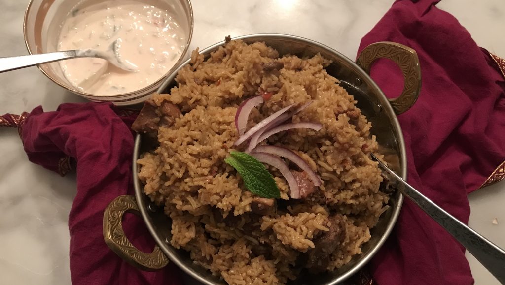 beautiful and taste lamb biryani and raita in a traditional indian serving bowl