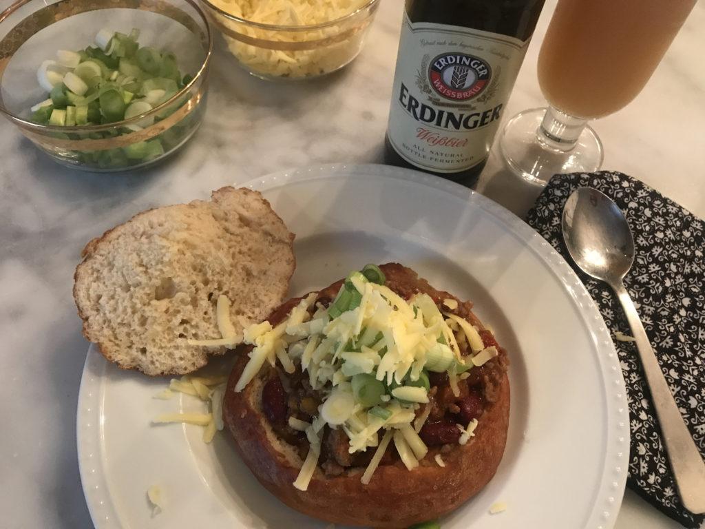 chili in a homemade pretzel bread bowl, topped with cheese and scallions with erdinger to wash it down