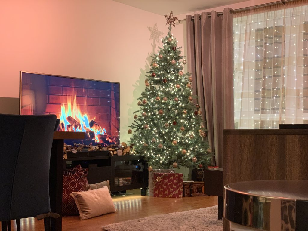 christmas tree with white lights and gifts below, and a digital fire on the tv