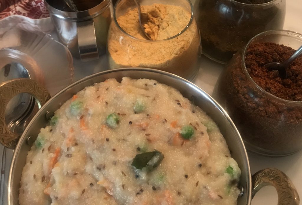 big pan of freshluy cooked upma, and all the pickles and podis to accompany it