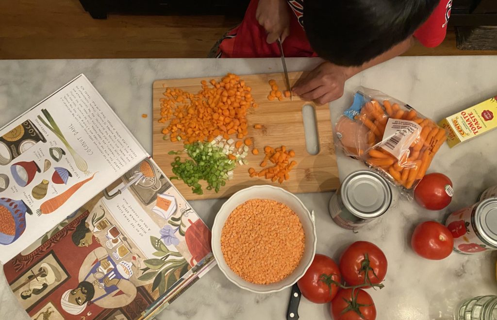 young chef making his new favorite dal from one of his books: coconut dal from